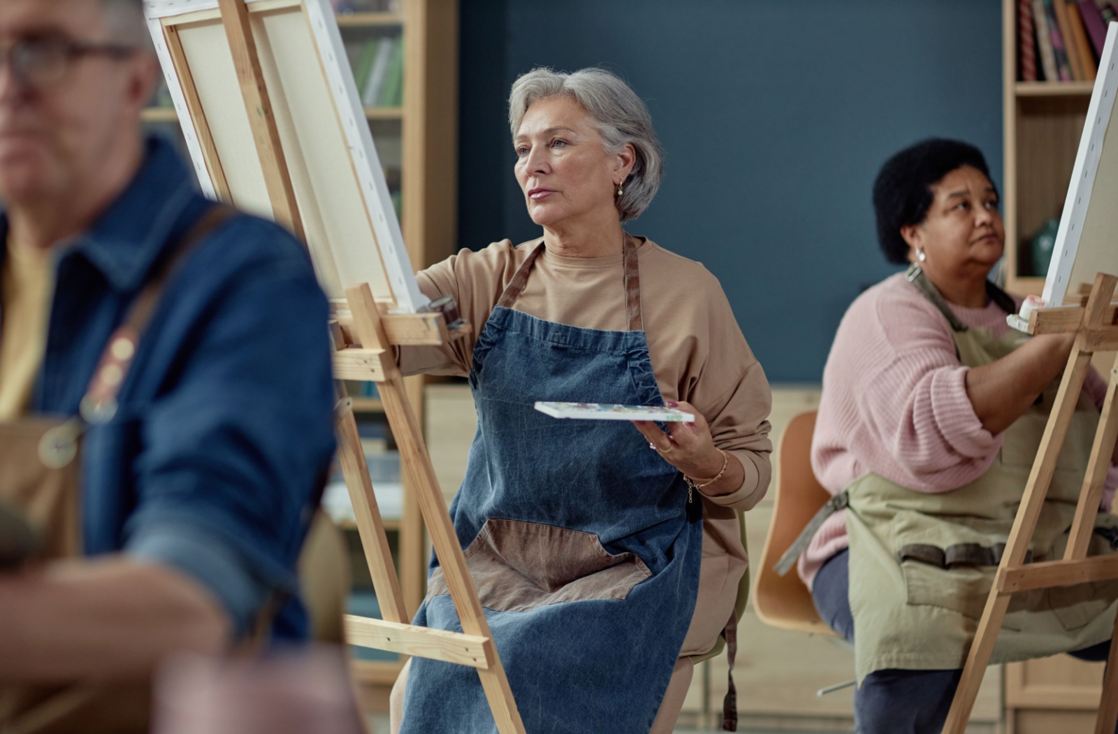 A focused senior takes part in a group art class in their assisted living community.