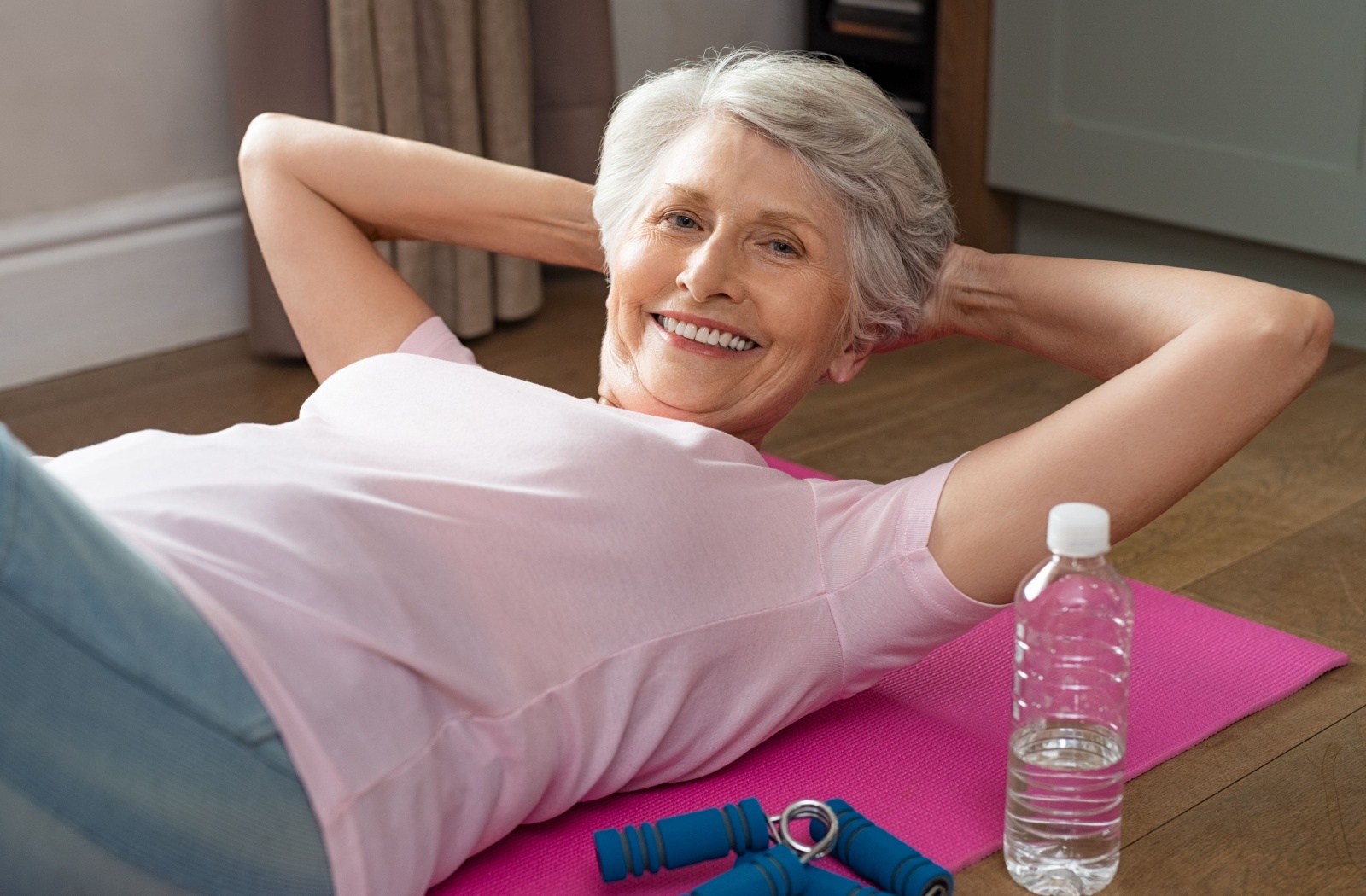 A senior woman doing sit ups, smiling and looking at the camera